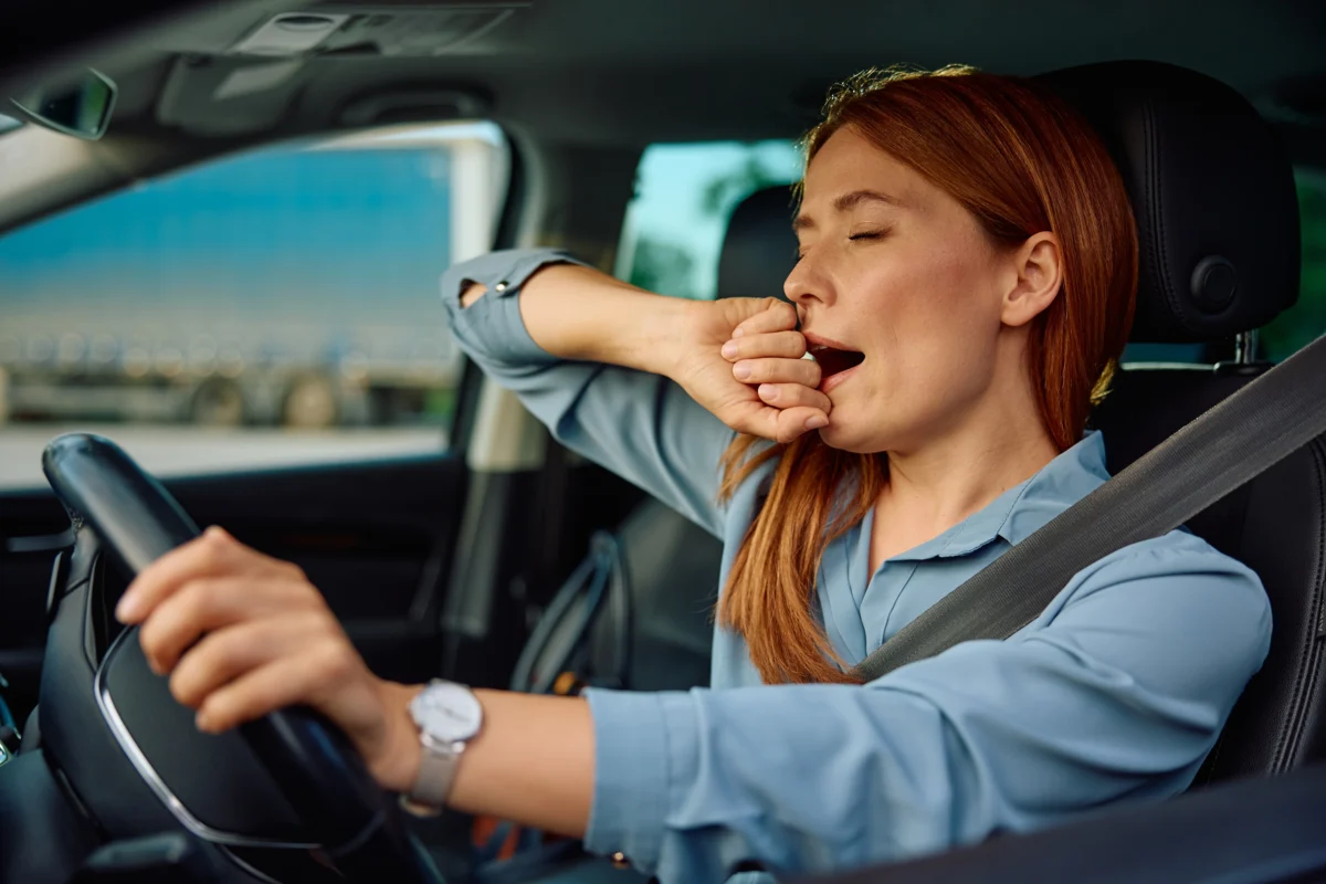 Exhausted woman yawning while driving